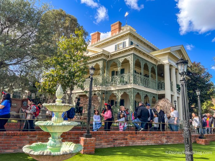 haunted mansion with tall white columns and stone fountain in front