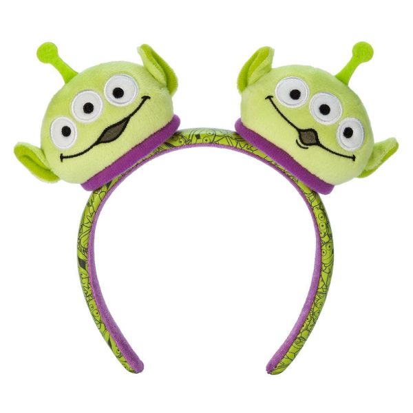 A Toy Story-themed plush ear headband featuring two green alien characters from the movies, with a purple band decorated with alien face prints.