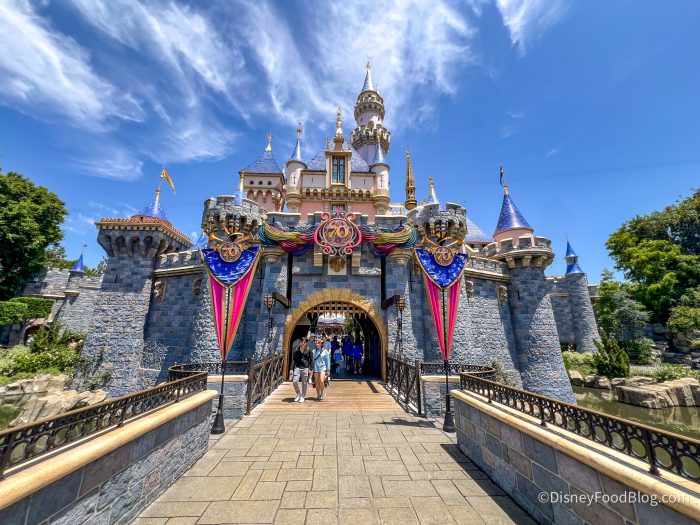 disneyland castle with pink and blue 70th anniversary banners