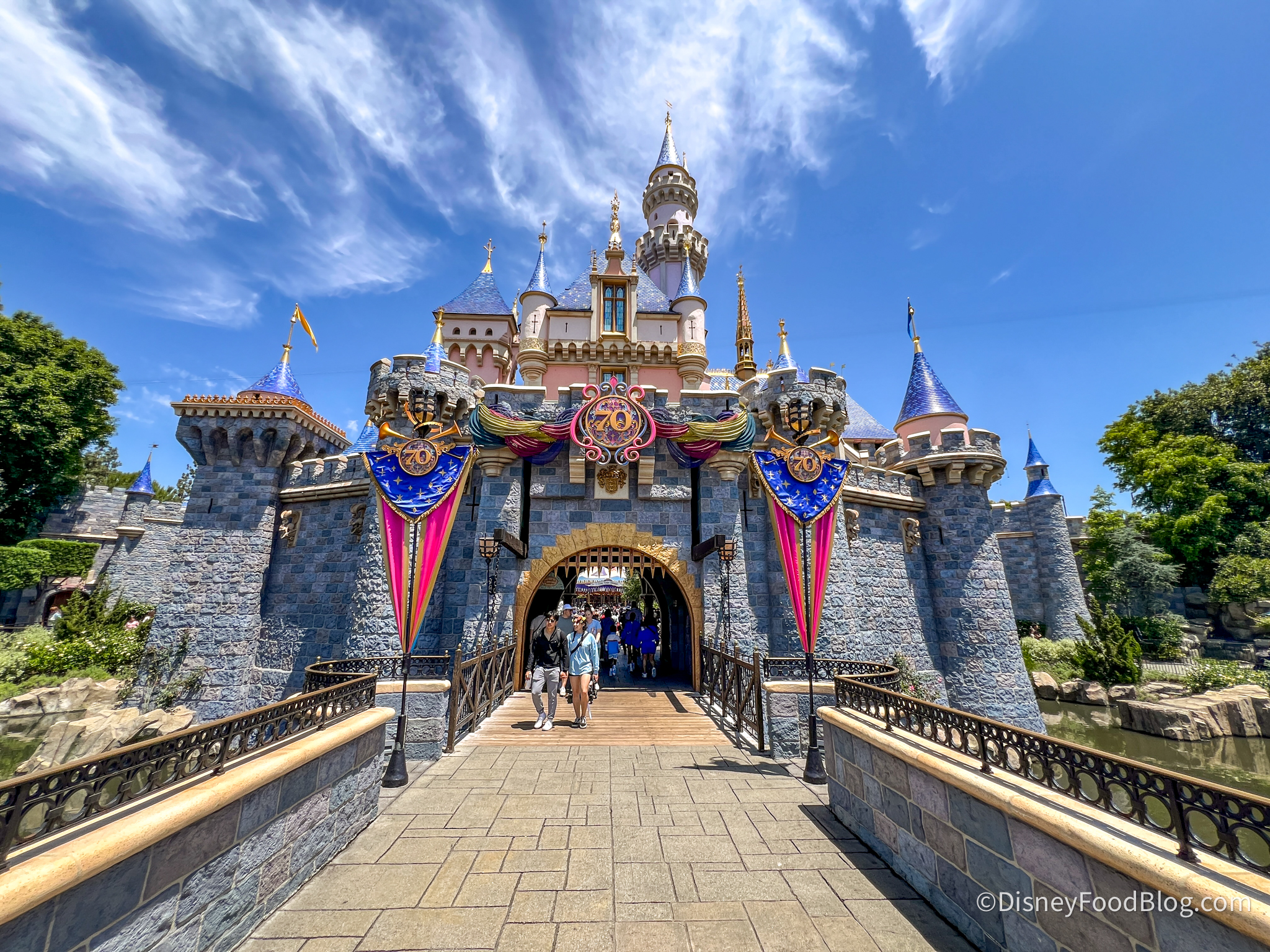 disneyland castle with pink and blue 70th anniversary banners